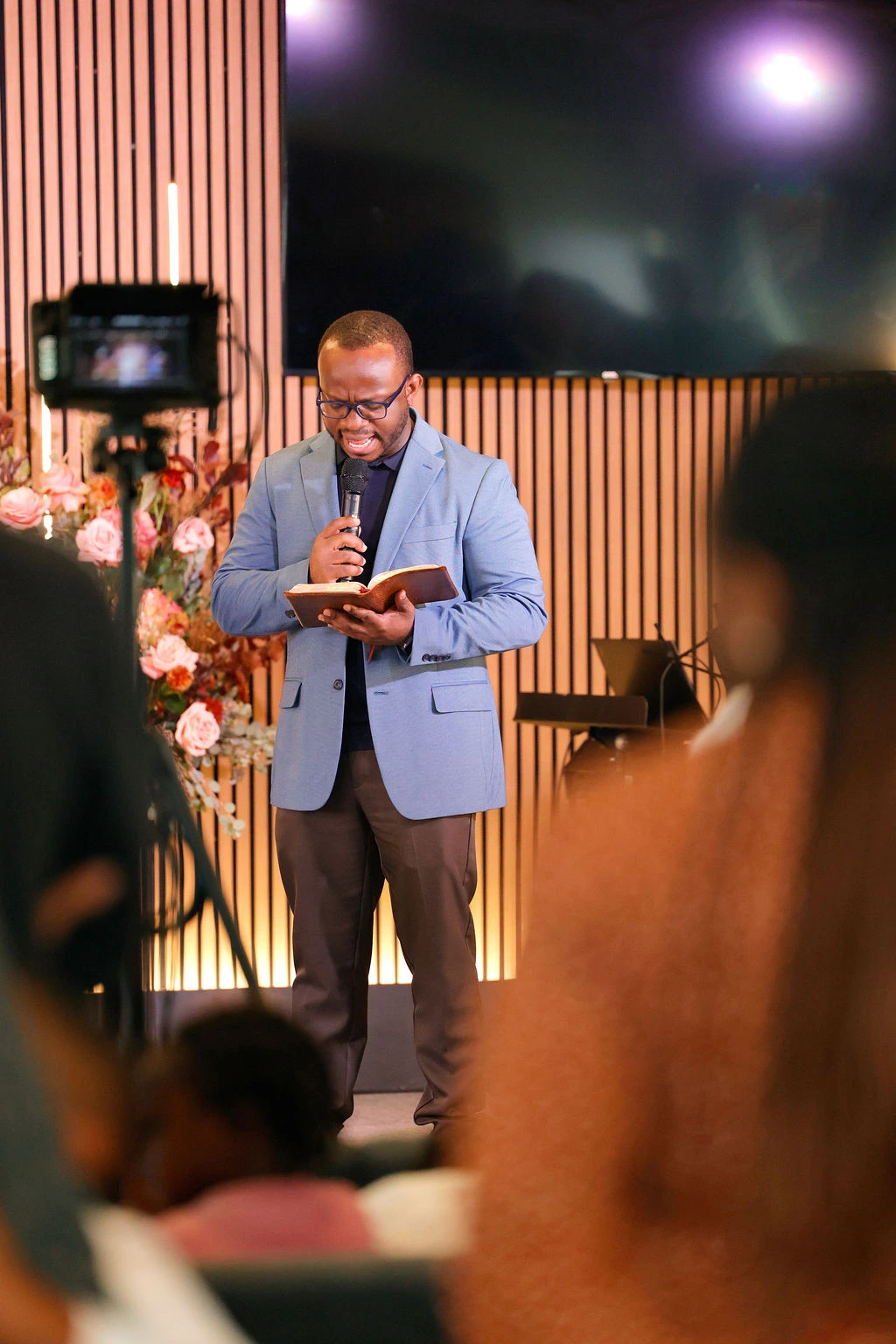 A speaker reading from the Bible into a microphone during a church service